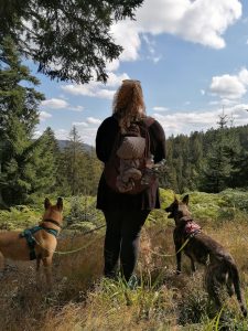 Pia mit zwei Schäferhunden am Waldrand